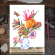 Blumenstillleben, ausgeführt mit Aquarellstiften. Acht Tulpen in einer chinesischen Vase, begleitet von einem Schmetterling und einer Raupe. Kunstdruck, auf einem Schreibtisch liegend.