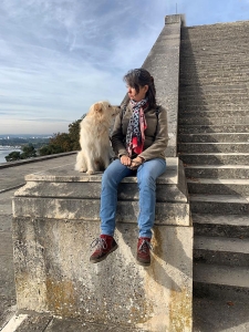 Eine Frau mit Hund sitzt auf einer steinernen Treppe.